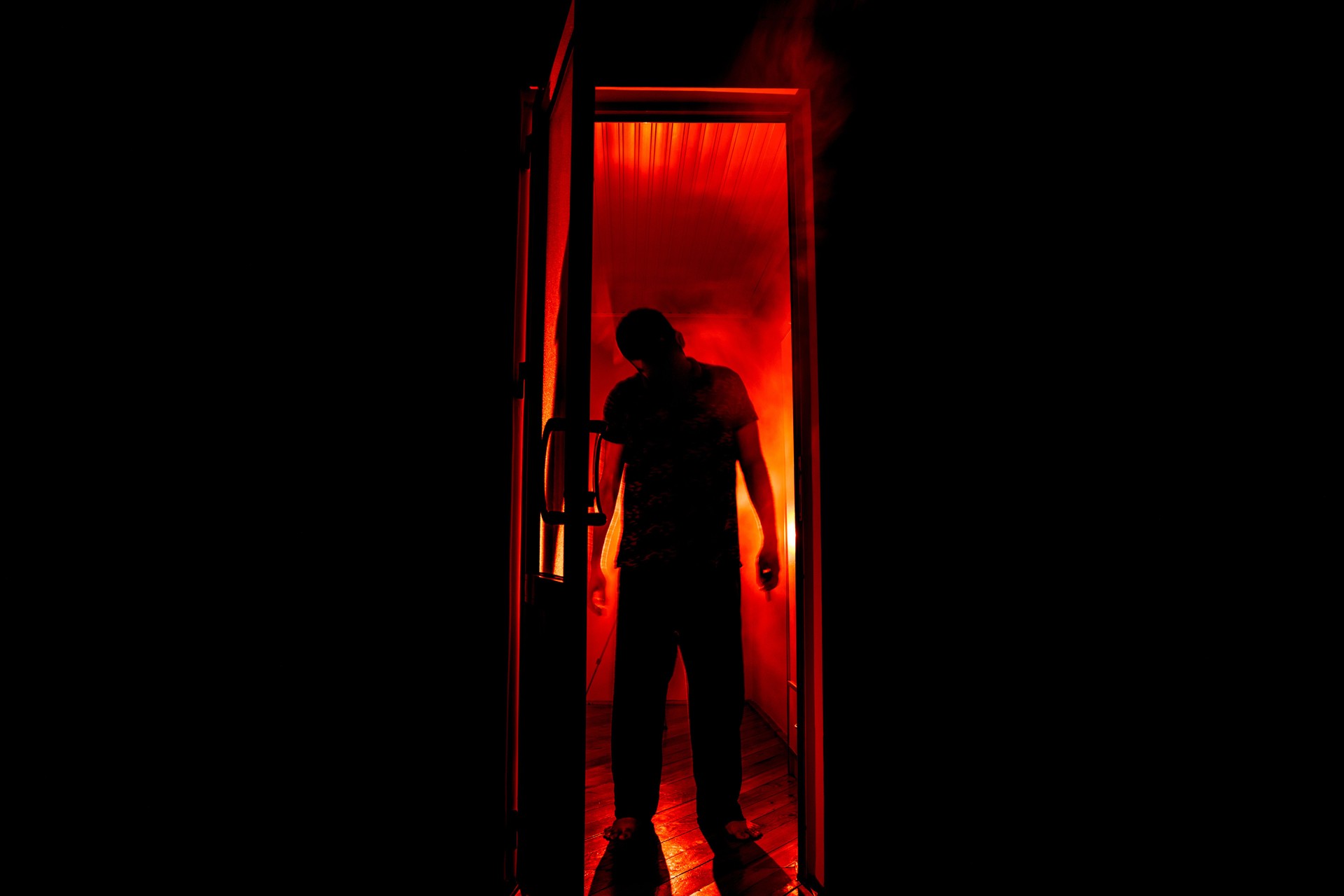 Silhouette of an unknown shadow figure on a door through a closed glass door. The silhouette of a human in front of a window at night. Scary scene halloween concept